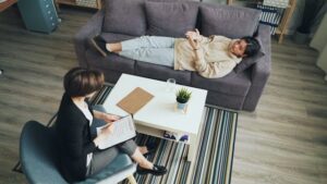 A woman is sitting on a couch with a man on the floor